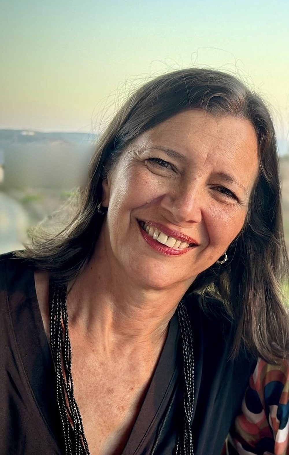 Retrato de Carolina Barrios, sonriendo, con el cielo al fondo